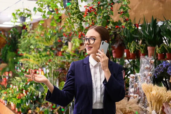 Propietaria mujer de negocios hablando por teléfono móvil en floristería — Foto de Stock