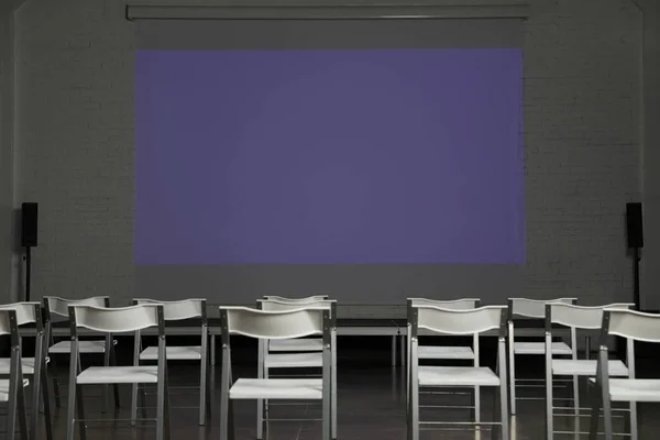 Empty conference room with projection screen and chairs