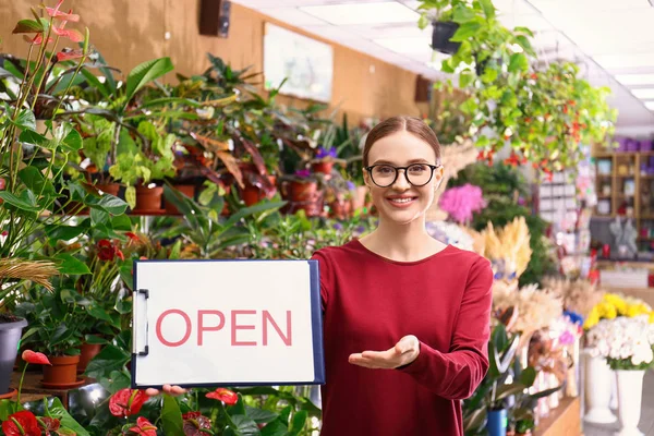Female business owner holding OPEN sign in flower shop