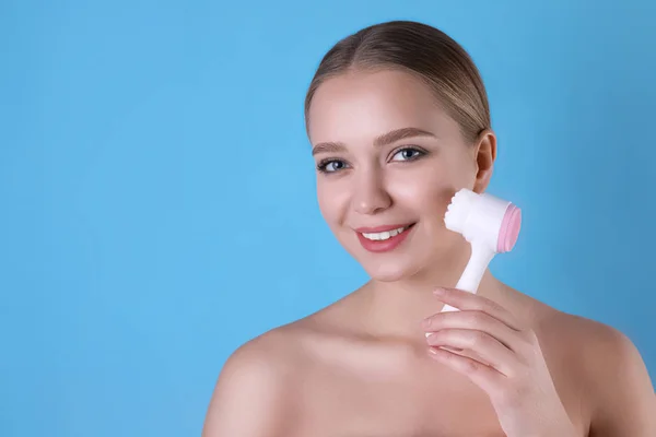 Giovane donna che lava il viso con spazzola detergente sulla schiena azzurra — Foto Stock