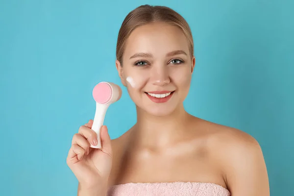 Giovane donna che lava il viso con pennello e schiuma detergente sulla luce — Foto Stock