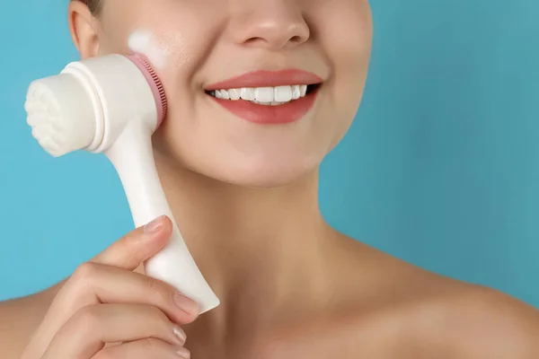 Giovane donna che lava il viso con pennello e schiuma detergente sulla luce — Foto Stock