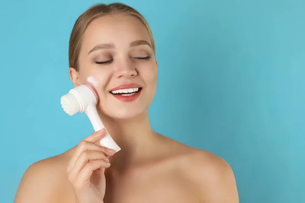 Ung kvinna tvätta ansiktet med borste och rengöring skum på ljus — Stockfoto