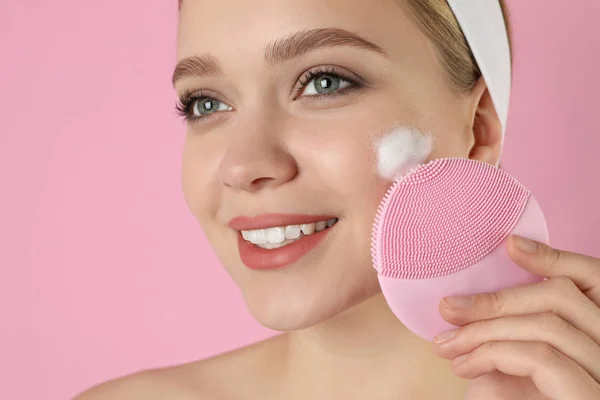 Giovane donna lavaggio viso con pennello e schiuma detergente rosa b — Foto Stock