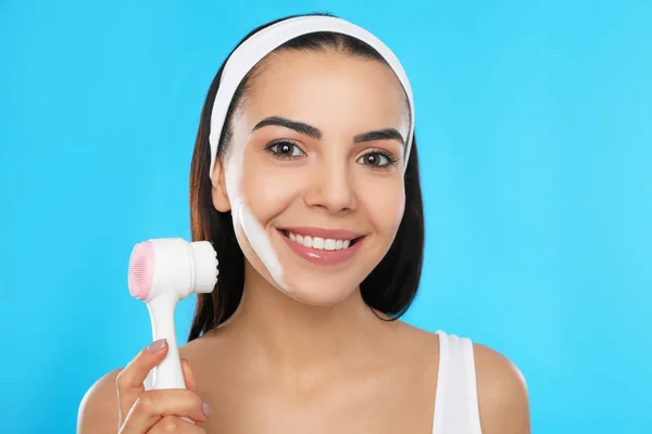 Mujer Joven Usando Cepillo Limpieza Facial Sobre Fondo Azul Claro —  Fotos de Stock