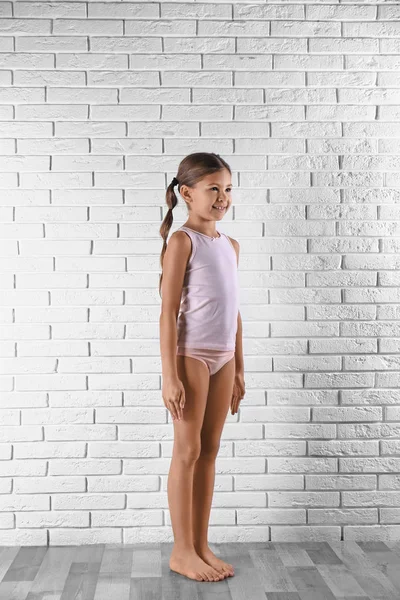 Petite fille mignonne en sous-vêtements près du mur de briques blanches — Photo