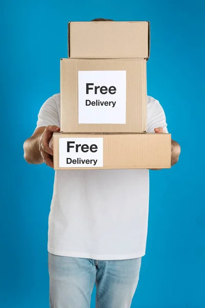 Erkek Kurye Elinde Çıkartmalı Paketler Açık Mavi Arka Planda Ücretsiz — Stok fotoğraf