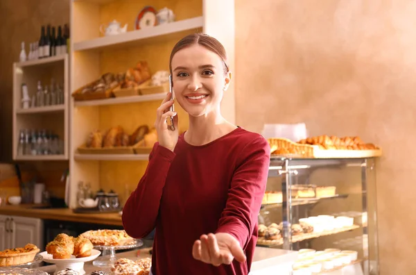 Proprietaria di affari femminile che parla a telefonino in panetteria — Foto Stock