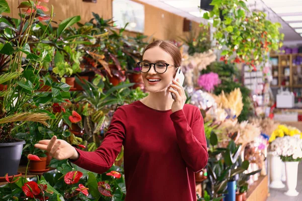 Propietaria mujer de negocios hablando por teléfono móvil en floristería — Foto de Stock