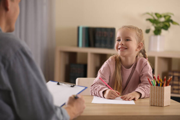 Little girl on appointment with child psychotherapist indoors