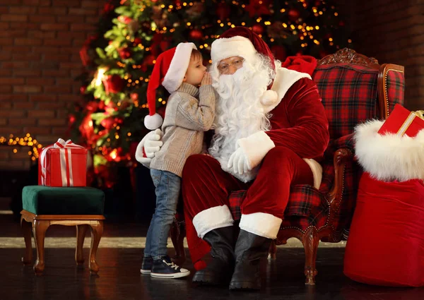 Santa Claus y el niño pequeño cerca del árbol de Navidad en el interior — Foto de Stock