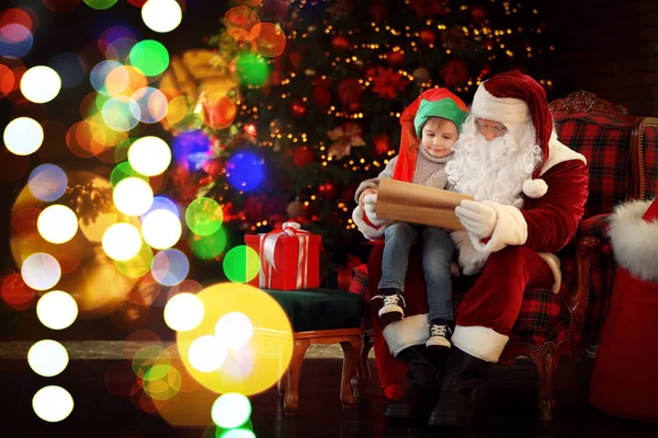 Santa Claus a malý chlapec u vánočního stromečku uvnitř — Stock fotografie