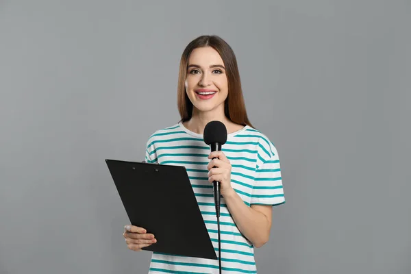 Ung Kvinnlig Journalist Med Mikrofon Och Urklipp Grå Bakgrund — Stockfoto