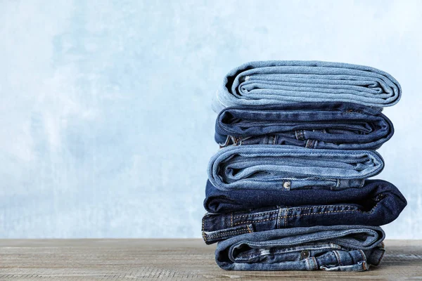 Stack Olika Jeans Träbord Mot Blå Bakgrund Plats För Text — Stockfoto