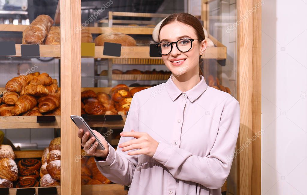 Female business owner with smartphone in bakery