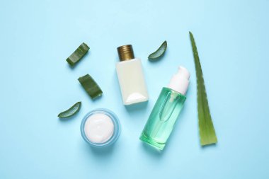 Açık mavi zemin üzerinde aloe vera ve kozmetik ürünleri ile düz bileşim yatıyordu