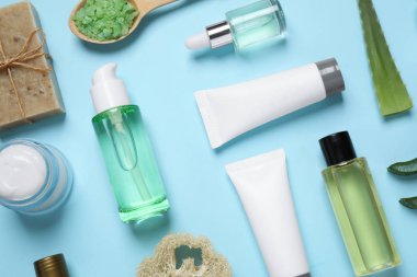 Açık mavi zemin üzerinde aloe vera ve kozmetik ürünleri ile düz bileşim yatıyordu