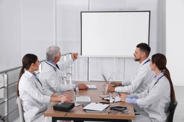 Doktorlar konferans sırasında kapalı alanda video projektörü kullanıyorlar.