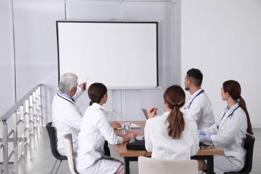 Doktorlar konferans sırasında kapalı alanda video projektörü kullanıyorlar.