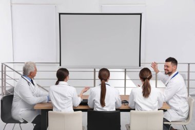 Doktorlar konferans sırasında kapalı alanda video projektörü kullanıyorlar.