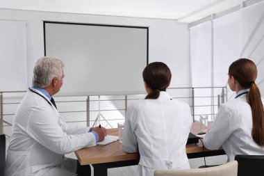 Doktorlar konferans sırasında kapalı alanda video projektörü kullanıyorlar.