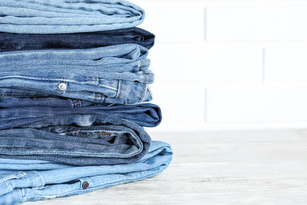 Stack Olika Jeans Vitt Träbord Mot Tegelvägg Plats För Text — Stockfoto