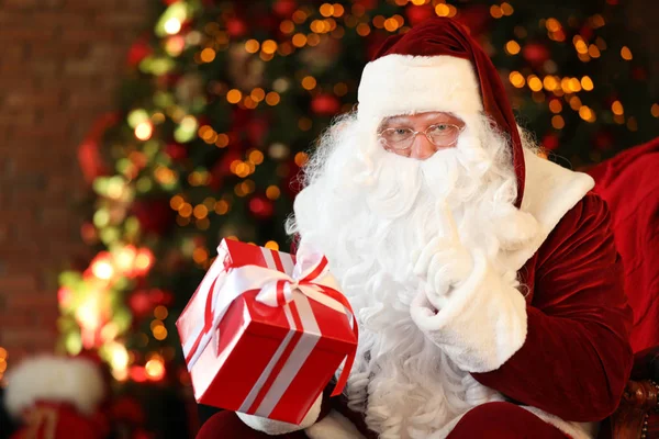 Santa Claus s dárkem u vánočního stromečku uvnitř — Stock fotografie