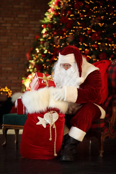 Père Noël avec sac cadeau près de l'arbre de Noël à l'intérieur — Photo