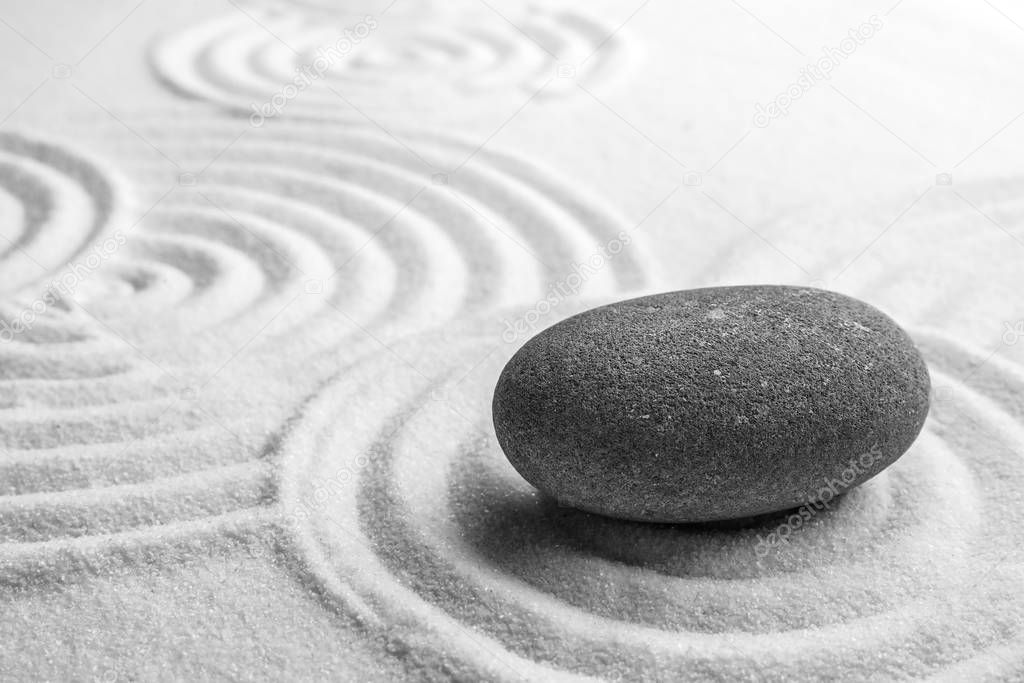 Grey stone on sand with pattern, space for text. Zen, meditation, harmony