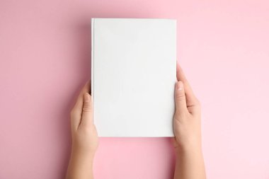 Pembe arka planda boş kapaklı kitap tutan kadın, üst görünüm