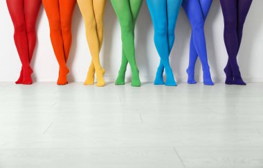 Beyaz duvarın yanında renkli tayt giyen kadınlar, yakın plan.