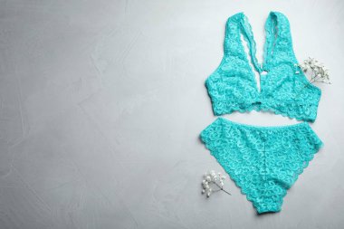 Zarif kadın iç çamaşırı ve açık gri taştan arka planda çiçekler, düz yatış. Metin için boşluk