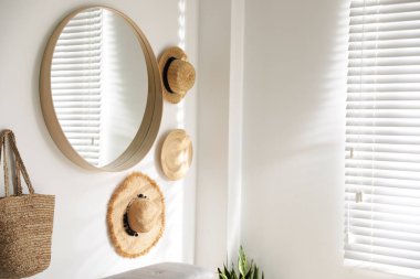 Beyaz duvarda asılı duran zarif yuvarlak ayna.