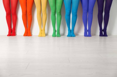 Beyaz duvarın yanında renkli tayt giyen kadınlar, yakın plan.