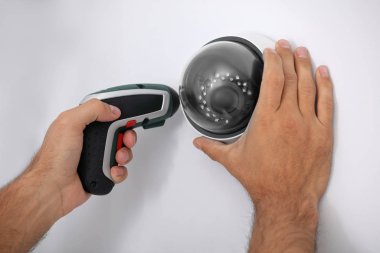 Teknisyen duvara kapalı devre kamera kuruyor.