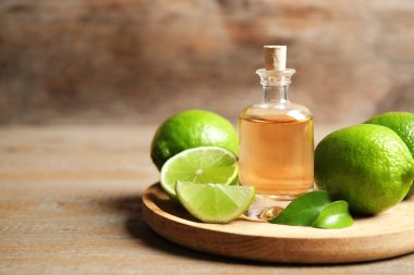 Tahta masanın üzerinde limon yağı ve narenciye meyveleri var.