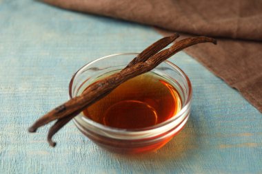 Aromatic homemade vanilla extract on light blue  wooden table, closeup clipart