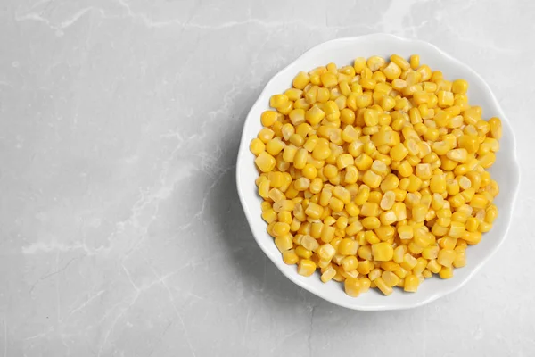Delicious canned corn in bowl on marble table, top view. Space for text