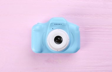 Açık mavi oyuncak kamera pembe ahşap arka planda, üst manzara
