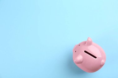 Açık mavi arka planda pembe domuzcuk kumbarası, üst manzara. Metin için boşluk