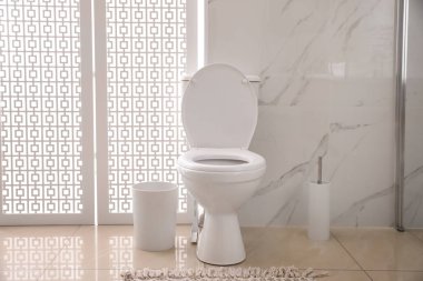 Kapalı alanda mermer duvarın yanında modern beyaz klozet.