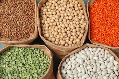 Masadaki kağıt torbalarda farklı tipte baklagiller ve tahıllar var. Organik taneler