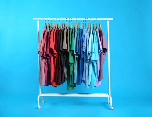 Ropa Colorida Colgando Estante Contra Fondo Azul Claro —  Fotos de Stock