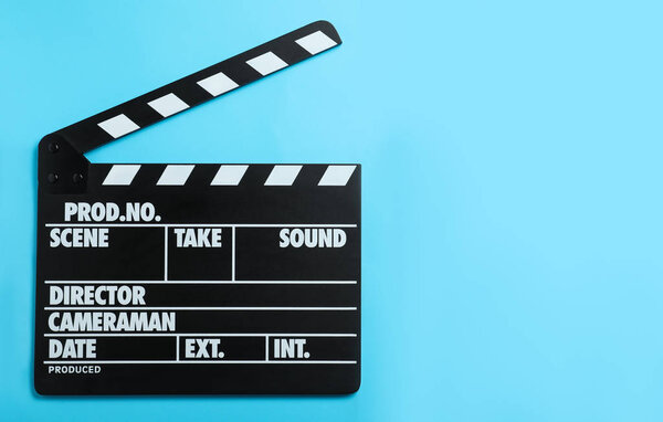 Clapper board on light blue background, top view with space for text. Cinema production