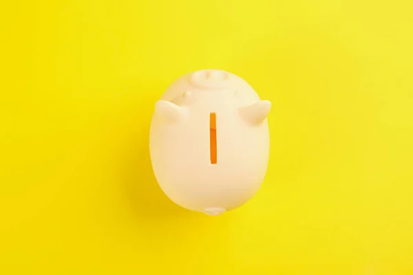 Beige piggy bank on yellow background, top view