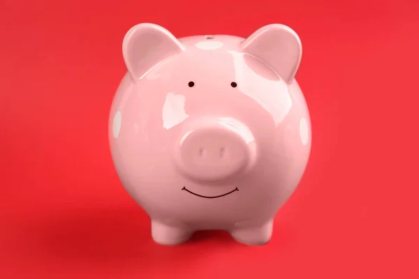 Cute pink piggy bank on red background