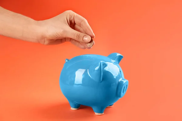 Mujer Poniendo Moneda Alcancía Sobre Fondo Naranja Primer Plano — Foto de Stock