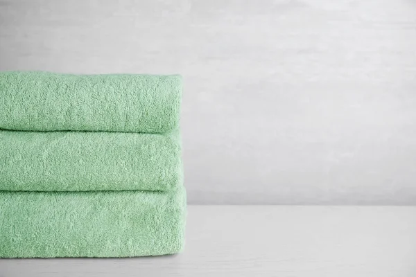 Pila di asciugamani puliti sul tavolo di legno bianco. Spazio per testo — Foto Stock