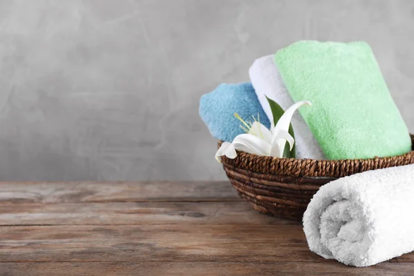 Плетений кошик зі складеними рушниками для ванни і красивою квіткою на волі — стокове фото