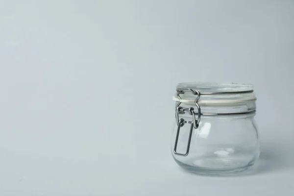 Closed empty glass jar on light background, space for text — Stock Photo, Image